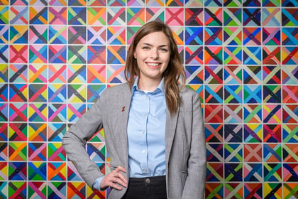 Image of a smiling teen girl wearing a blazer, against a colorful geometric-patterned background.