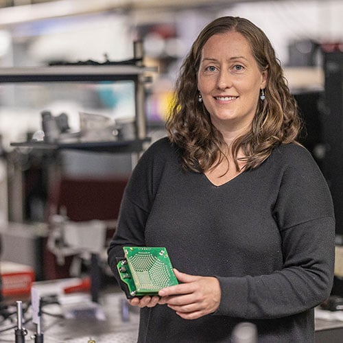 Imaging scientist Laura in a computational imaging lab holing a piece of imaging equipment 