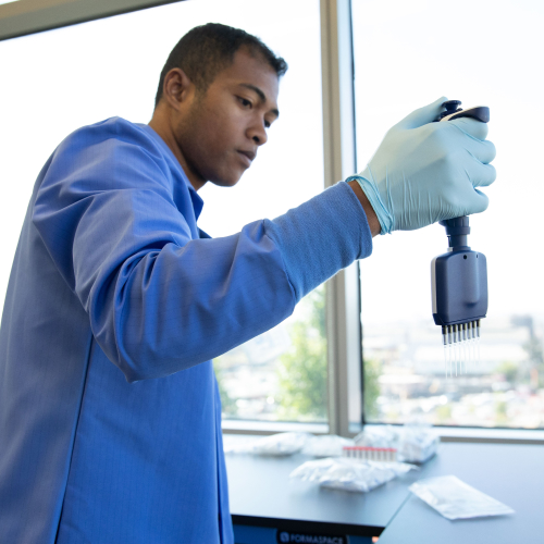 A scientist wears a blue lab coat in the lab