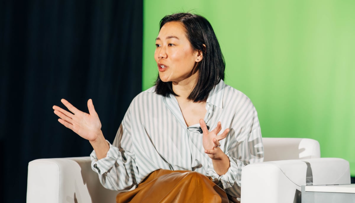 Priscilla Chan speaks while sitting in a white chair on a stage at NVIDIA GTC. A green and black background is behind her. 