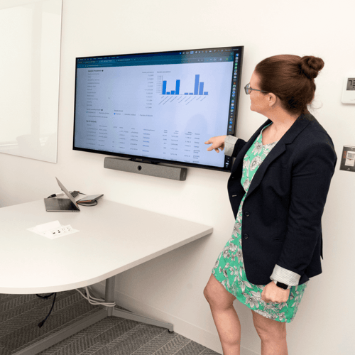 Samantha Baxter, a senior clinical genomics specialist, stands and points towards a computer screen displaying the GeniE tool.