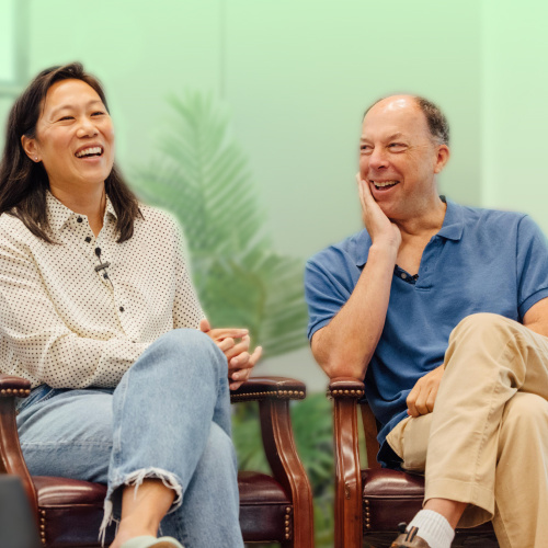 Priscilla Chan and Steve Quake, head of science, are seated in armchairs, smiling and laughing during a discussion, with a light background and greenery visible behind them.