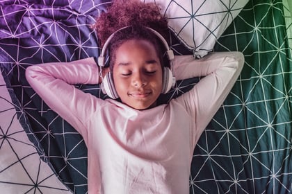 Kid laying in bed with headphones on